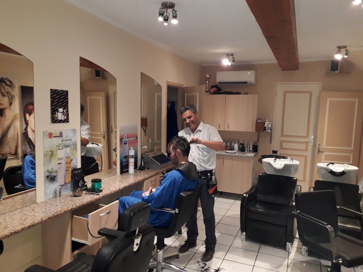 Carlos souriant en train de couper les cheveux d’un client dans son salon