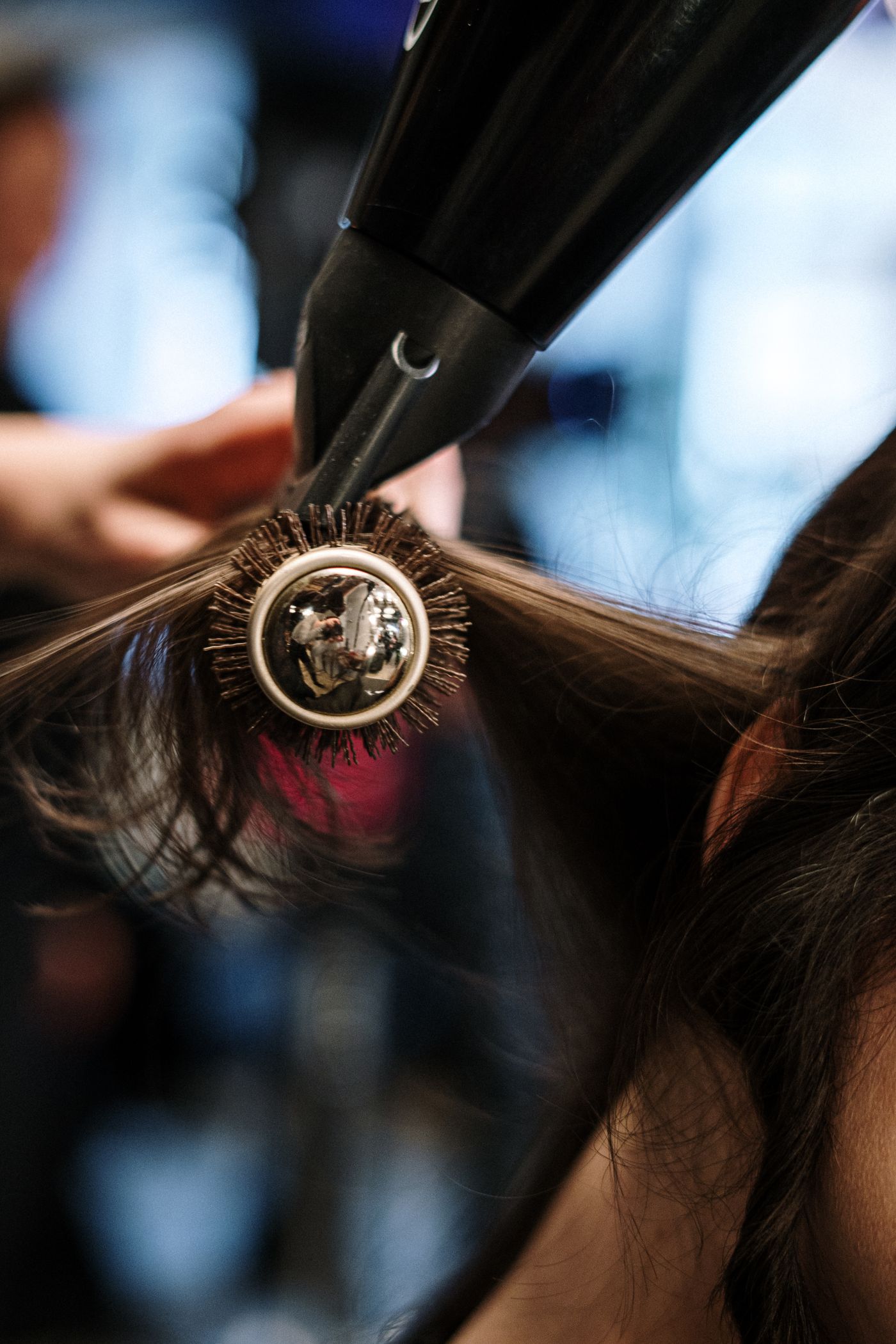 Brosse ronde et sèche-cheveux en action sur de longs cheveux bruns