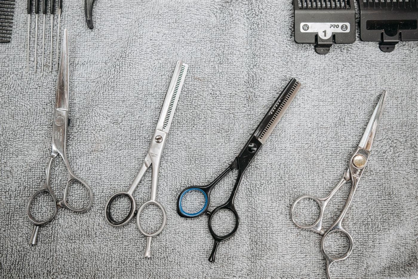 Quatre paires de ciseaux de coiffeur alignées sur une serviette grise