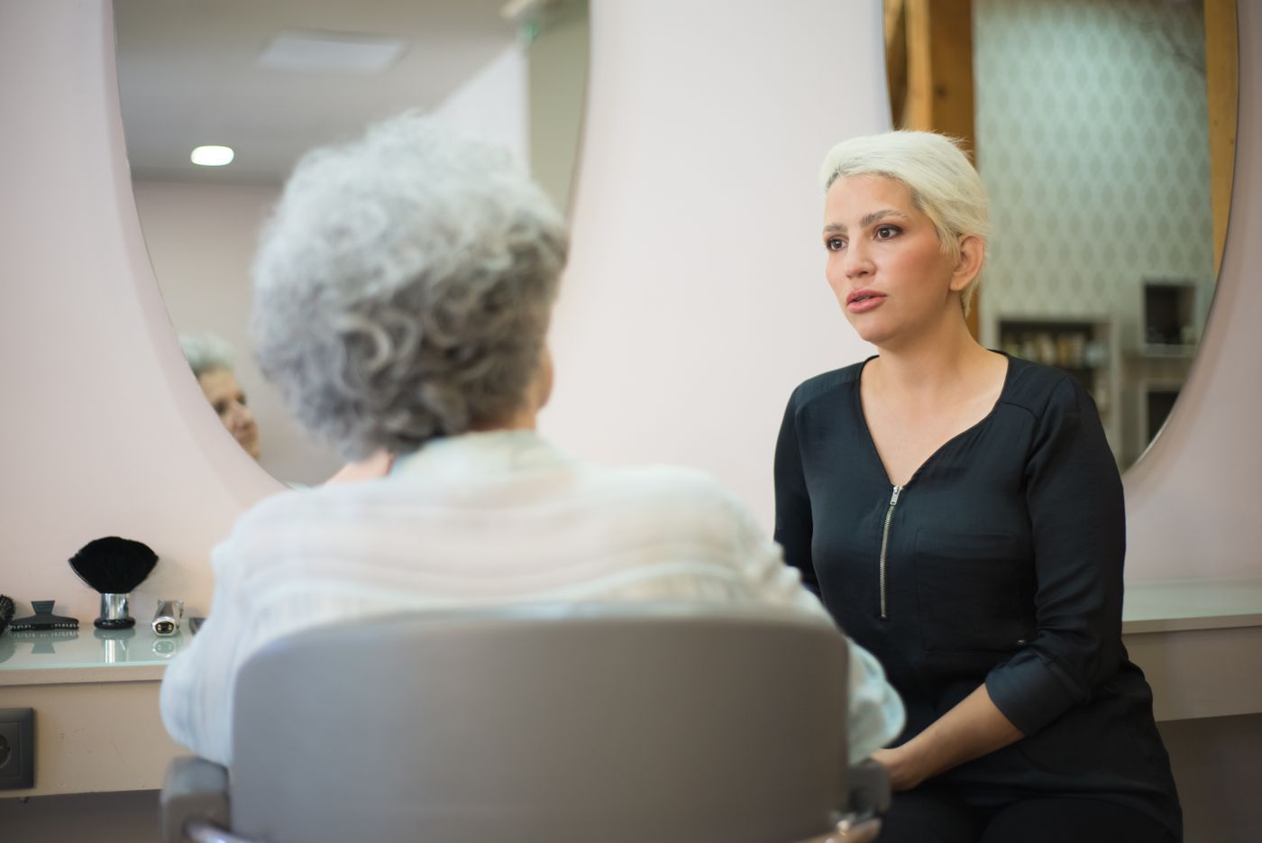 Deux femmes échangent sur la coupe idéale devant un miroir arrondi