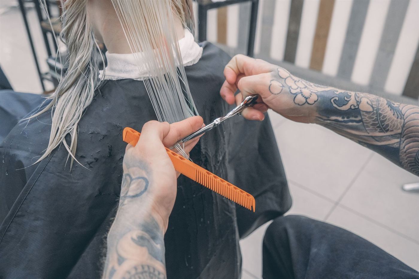 Coiffeur coupant des cheveux longs et blonds aux ciseaux
