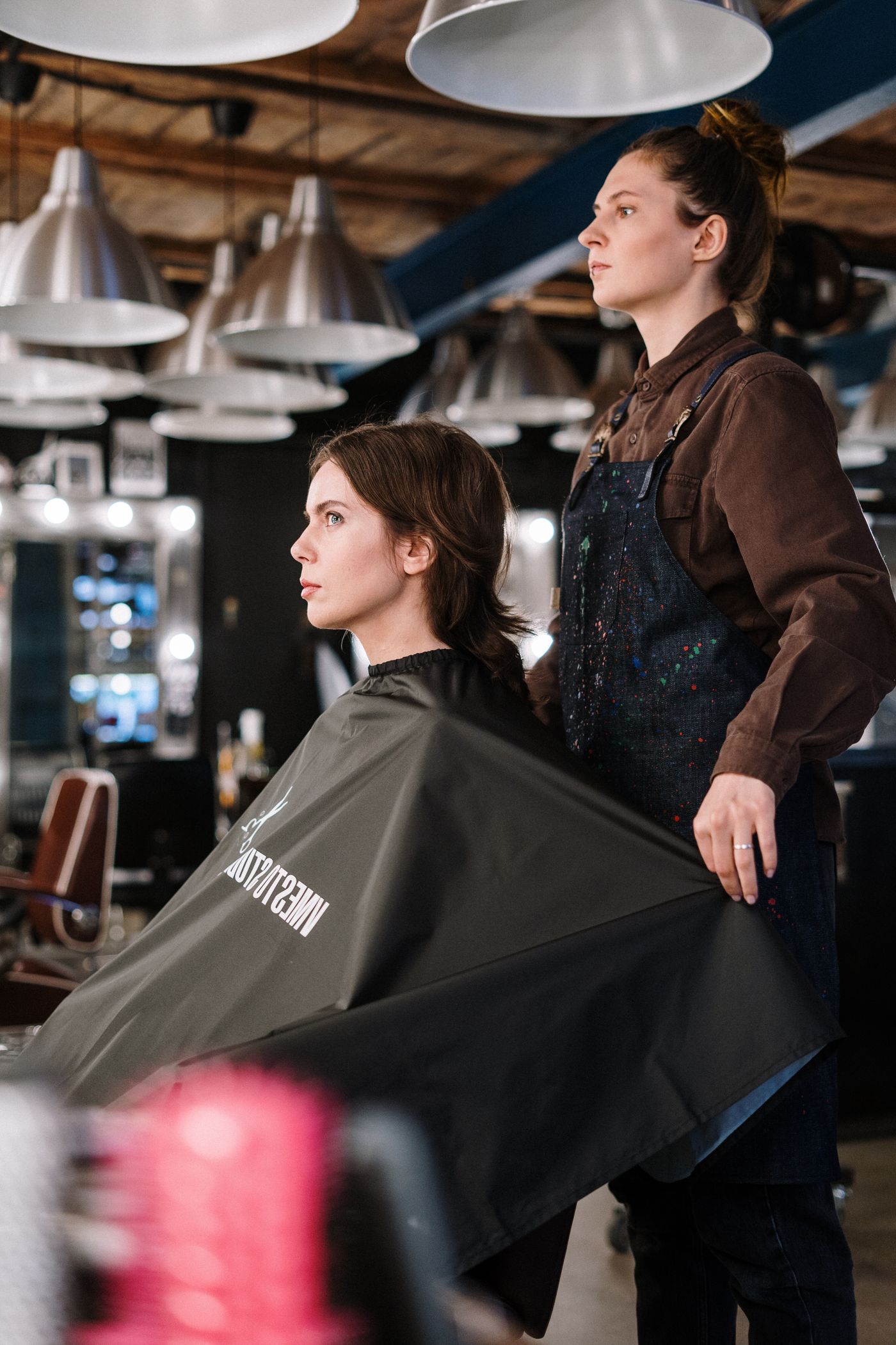 Une cliente installée sous la cape pendant que la coiffeuse prépare sa coupe