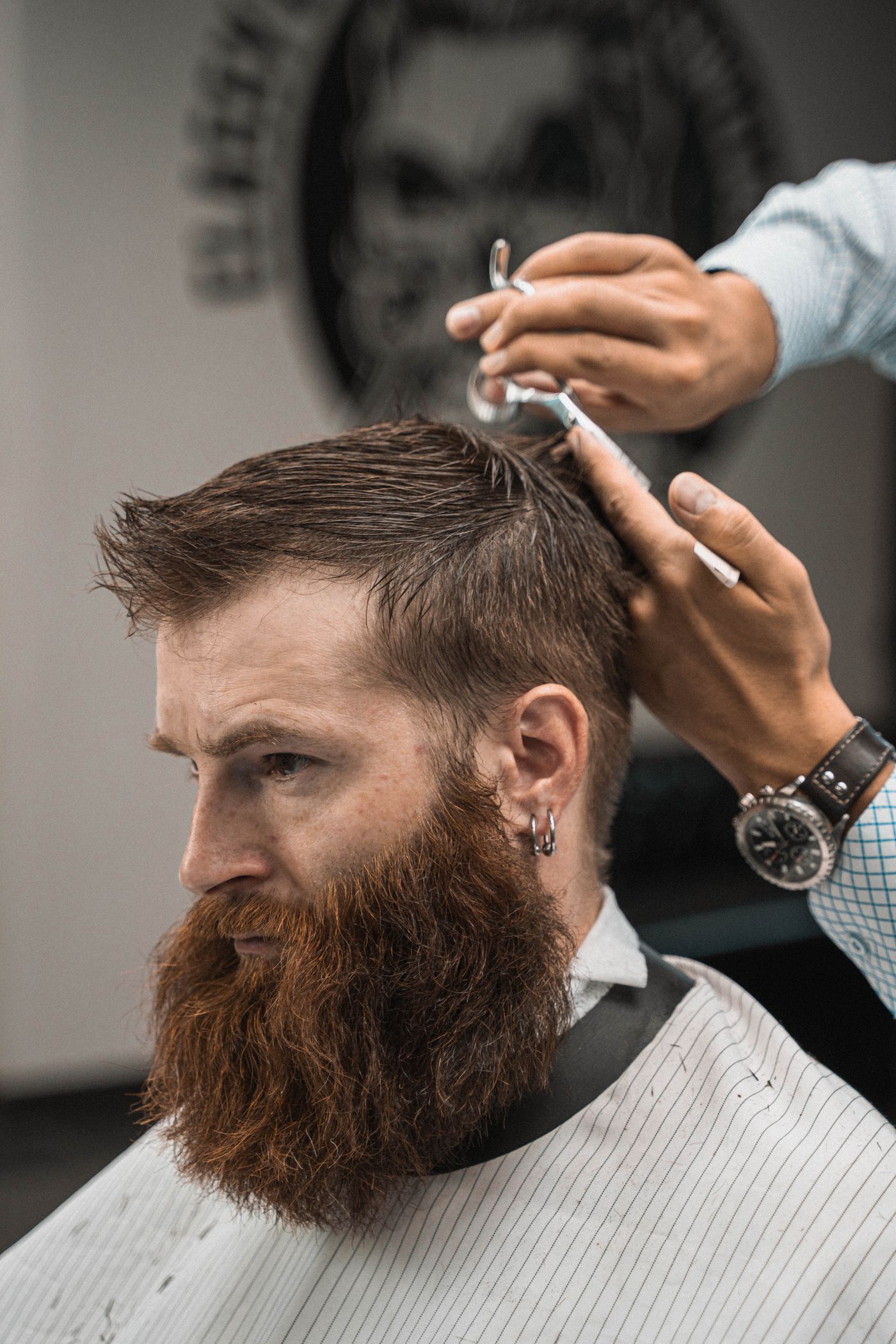 Coiffeur taillant au ciseau les cheveux et la barbe d’un client, profil net