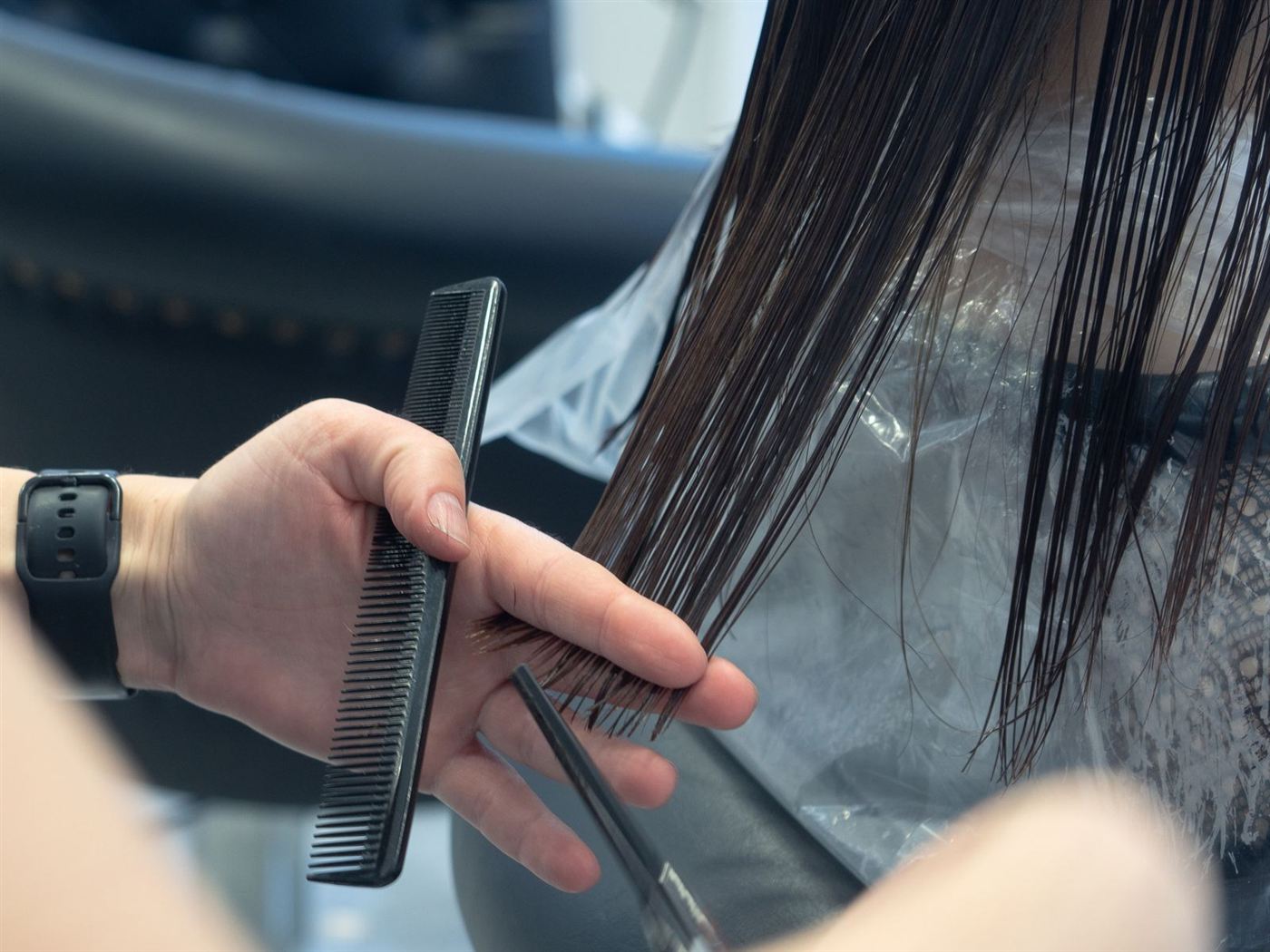 Mèche de cheveux mouillés tenue entre peigne et ciseaux